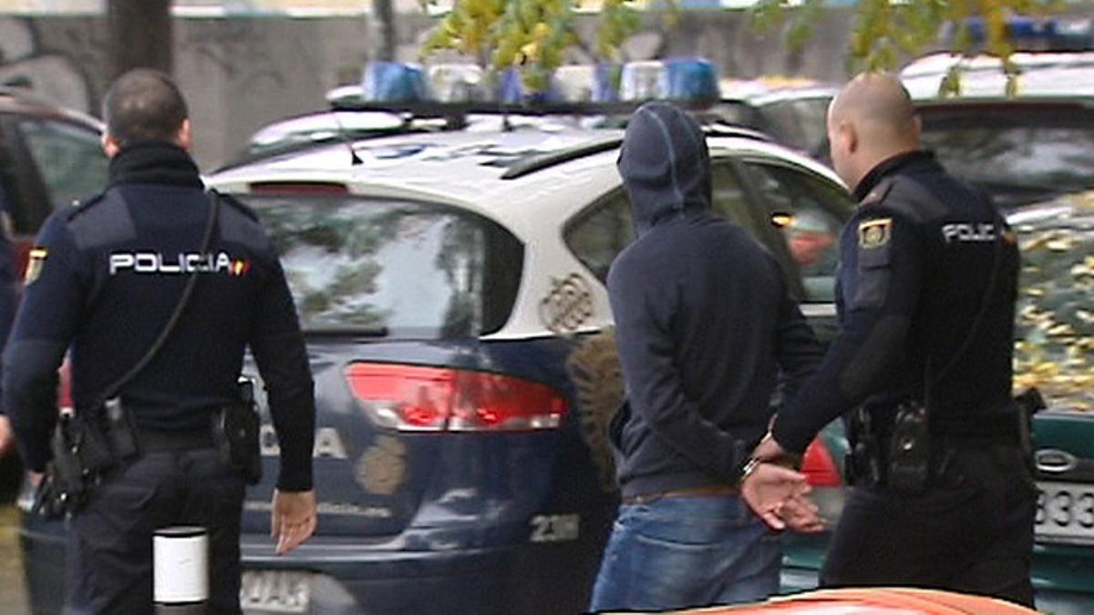 Agentes de la Policía Nacional conducen a uno de los detenidos en la reyerta entre radicales del Atlético y del Deportivo