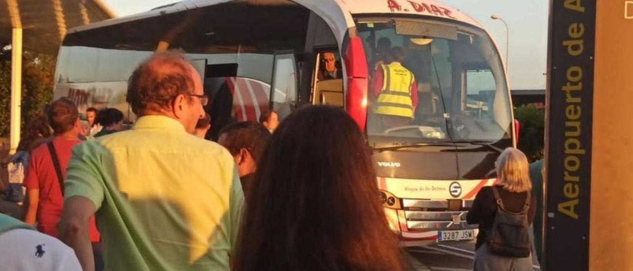 Pasajeros afectados por la cancelación del vuelo de Asturias a Valencia del pasado jueves se encaminan hacia el autobús que los trasladó al destino.