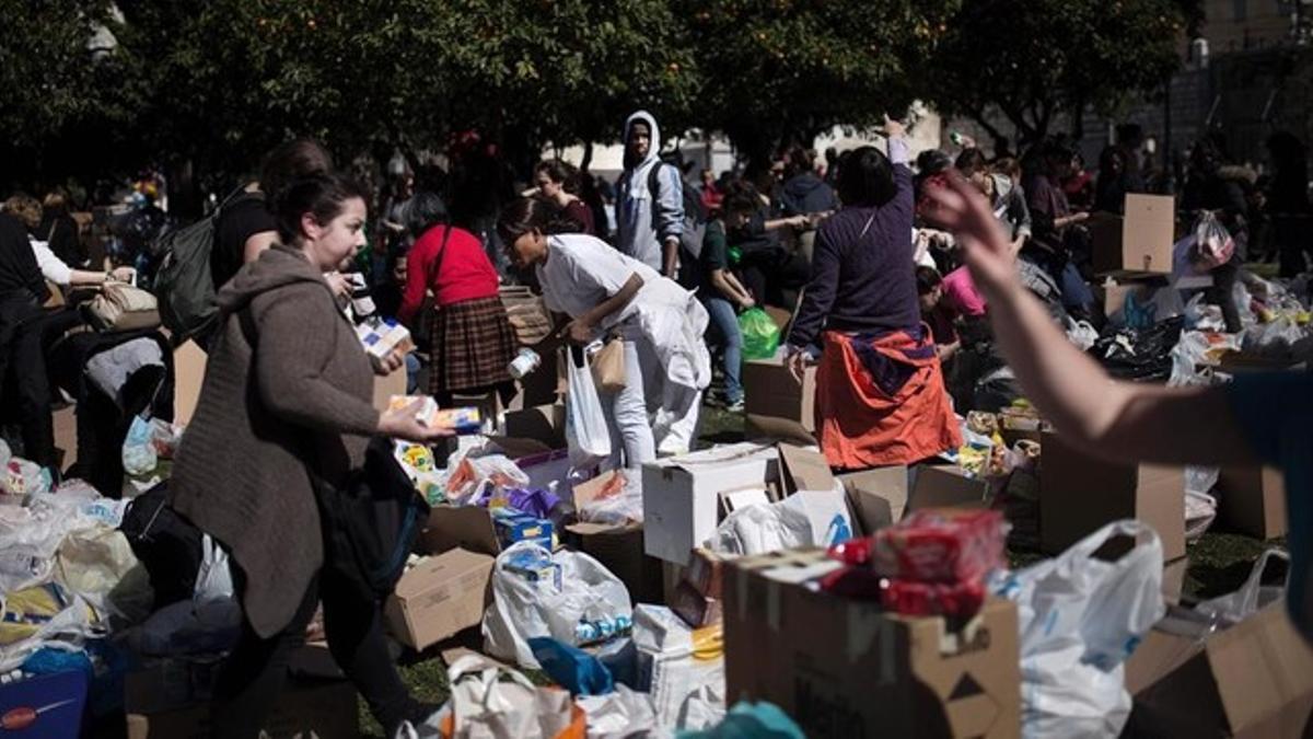 Un grupo de voluntarios reune las bolsas y cajas que han traído vecinos de Atenas para los refugiados.