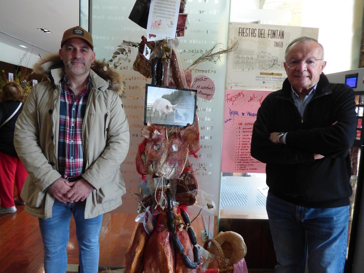 César Antón y Benjamín Alba ante el árbol de productos de la rifa de la fiesta.