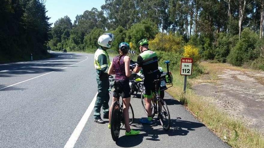 Agentes de la Guardia Civil de Tráfico entregando folletos informativos a dos ciclistas. // Guardia Civil