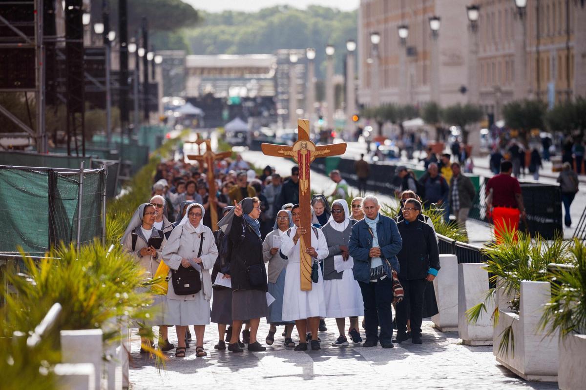 Faithful walk with a cross on Via della Conciliazione street near the Vatican, a day prior to the start of the conclave in Rome on May 6, 2025. (Photo by Dimitar DILKOFF / AFP)