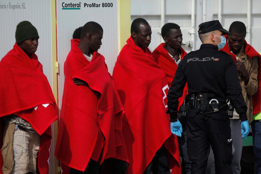 Migrants stand upon arriving on a rescue boat at ...