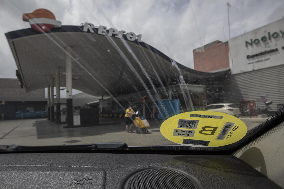 Un coche con etiqueta amarilla de la DGT, dispuesto a echar gasolina junto a la Ronda Litoral