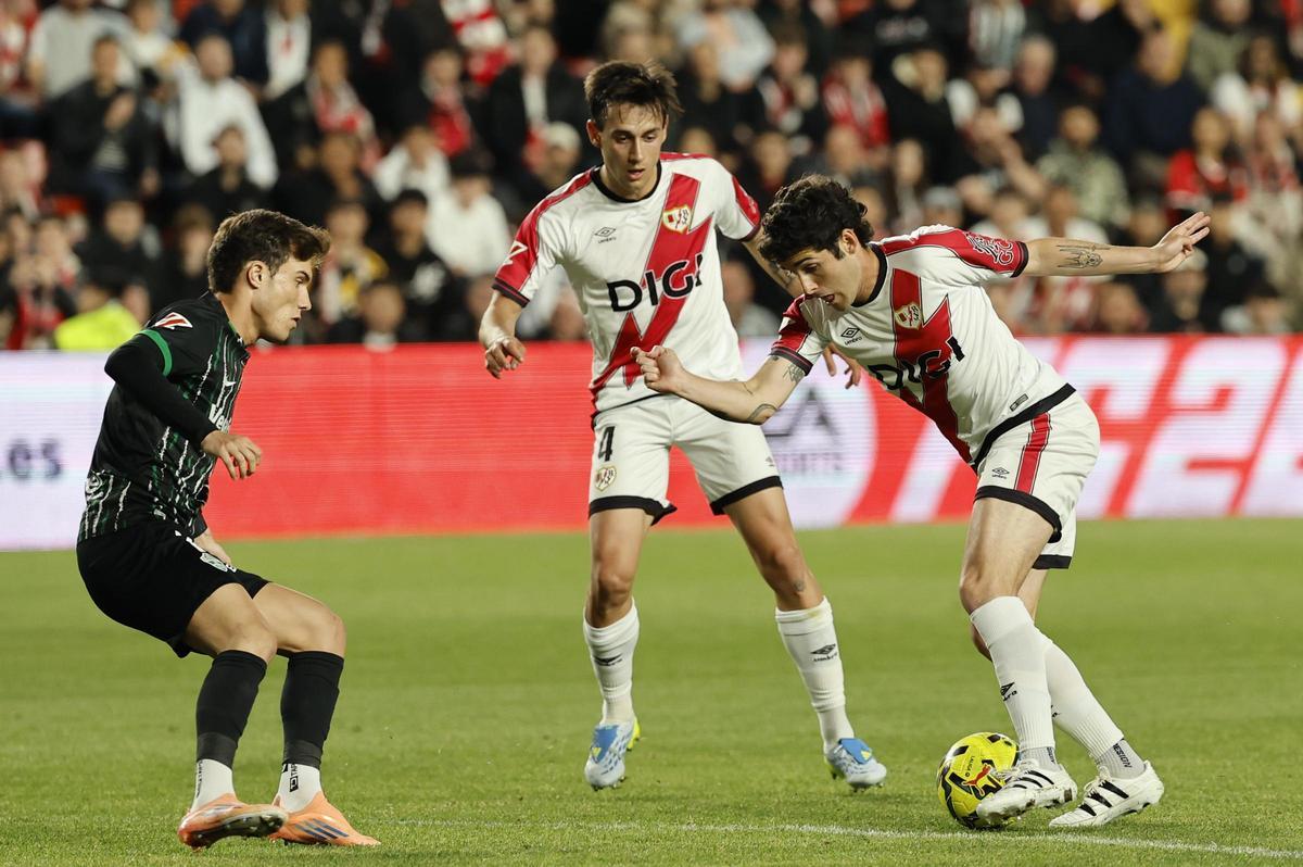 El delantero del Rayo Sergio Camello (d) juega un balón ante Yago Santiago (i), del Elche, durante el partido de LaLiga de fútbol que Rayo Vallecano y Elche CF disputan este viernes en el estadio de Vallecas, en Madrid.