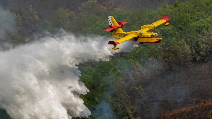 Un avión dispersa agua para sofocar las llamas de un incendio en Lugo.