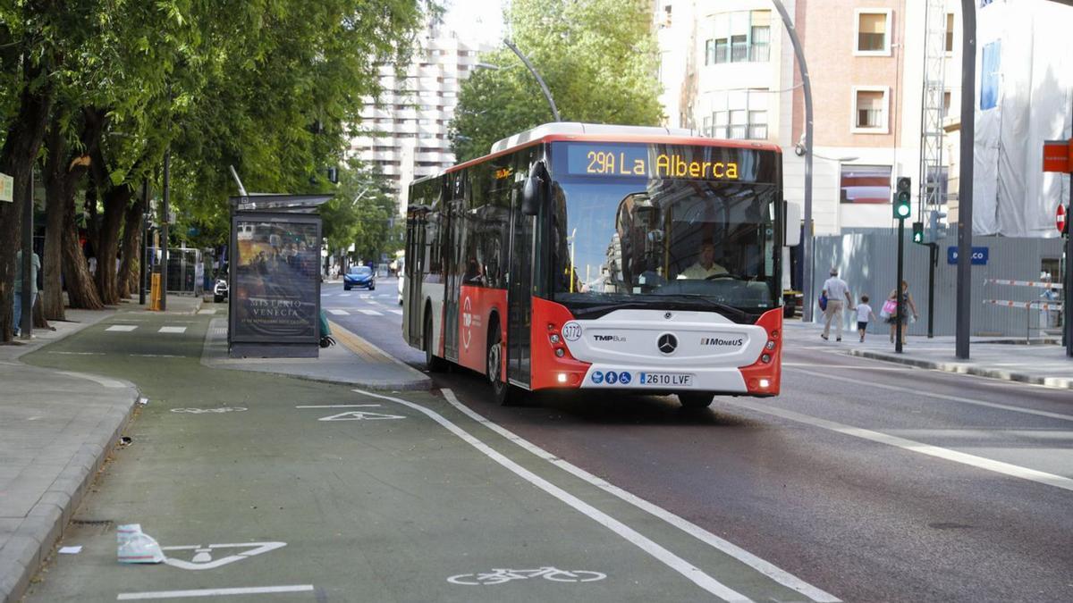 Un autobús y una ciclista, circulando por las nuevas zonas destinadas al transporte público y a los vehículos de movilidad personal del plan de movilidad