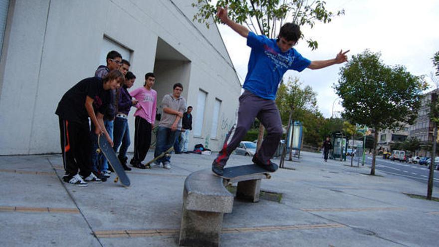 Un joven practica con su &quot;skate&quot; en un banco junto al centro de salud en Chapela