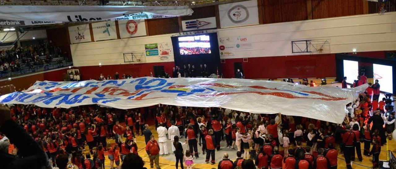 Los deportistas del Grupo despliegan una enorme bandera como cierre del acto de presentación de las secciones.