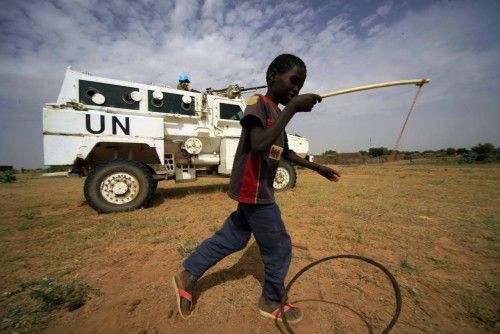 Un niño juega en frente de fuerzas de paz de la UNAMID