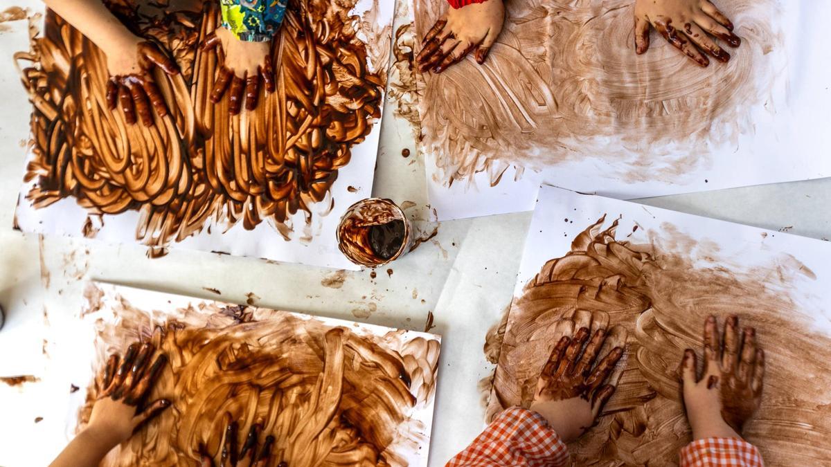 Alumnado de la escuela Arenal de Llevant de Barcelona pintando con las manos usando chocolate como pintura.