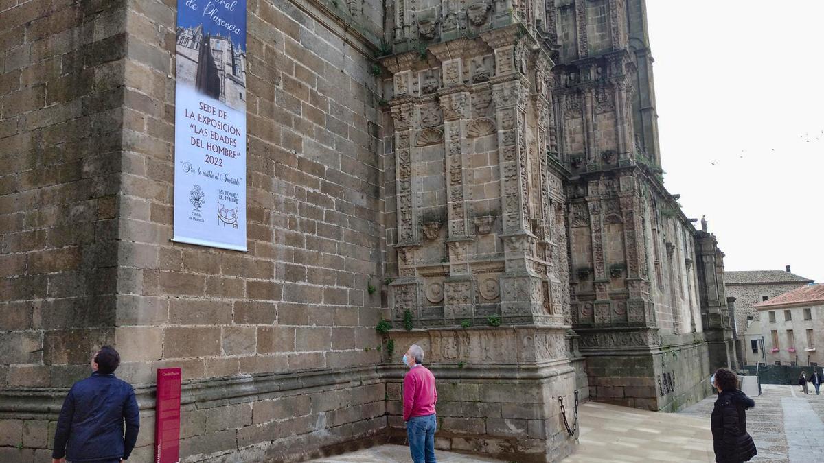 Varias personas observan el cartel que indica que la catedral acogerá las Edades del Hombre.