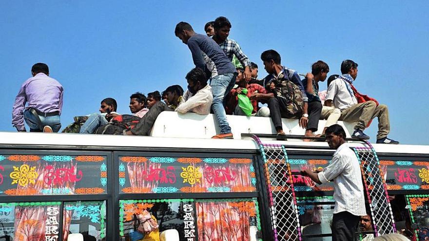 Un grupo de ciudadanos indios se sube al techo de un autobús para regresar a sus casas tras el anuncio del confinamiento del país anunciado por el primer ministro.