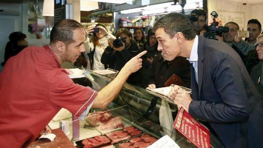 Sánchez escucha a un carnicero en Barcelona.  // Efe