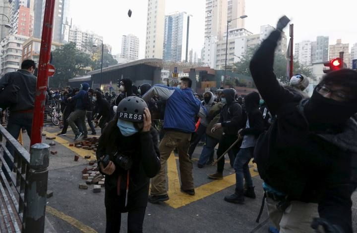 Protesters throw bricks as a journalist takes cover during a clash with riot police at Mongkok district in Hong Kong
