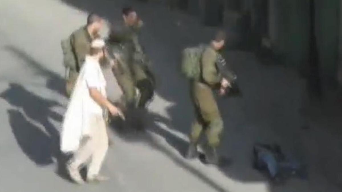 Un colono, con un pistola, tras abatir a un palestino en Hebrón.