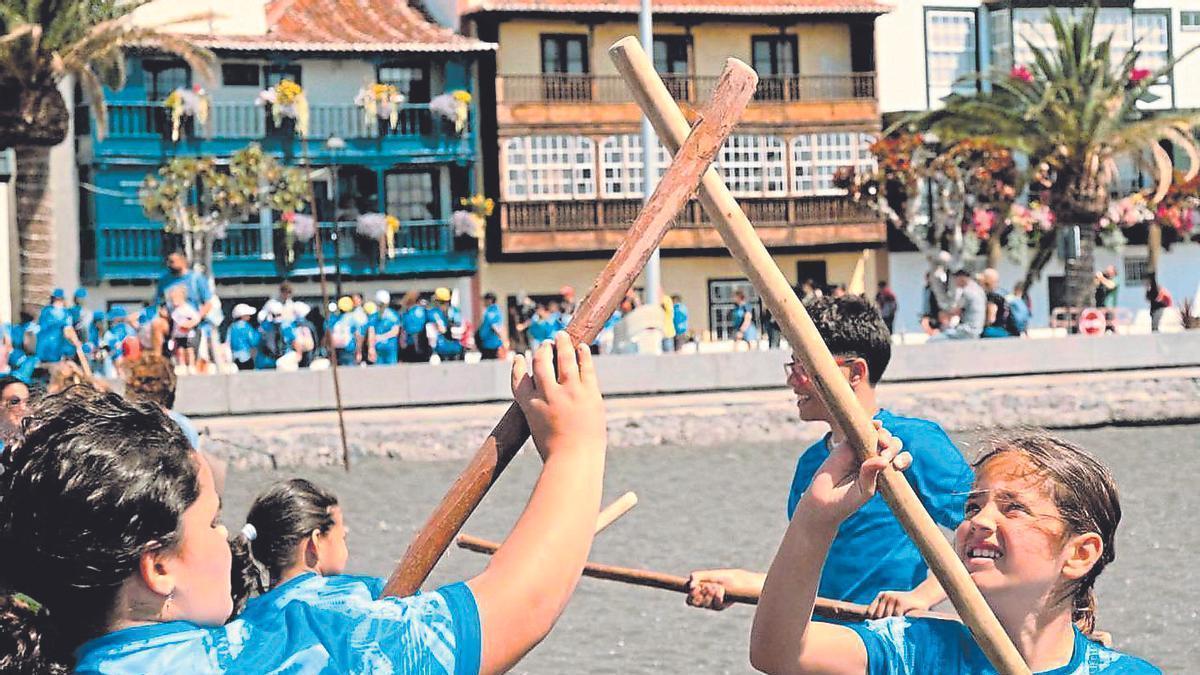 Unos niños practican el juego del palo canario en una playa.