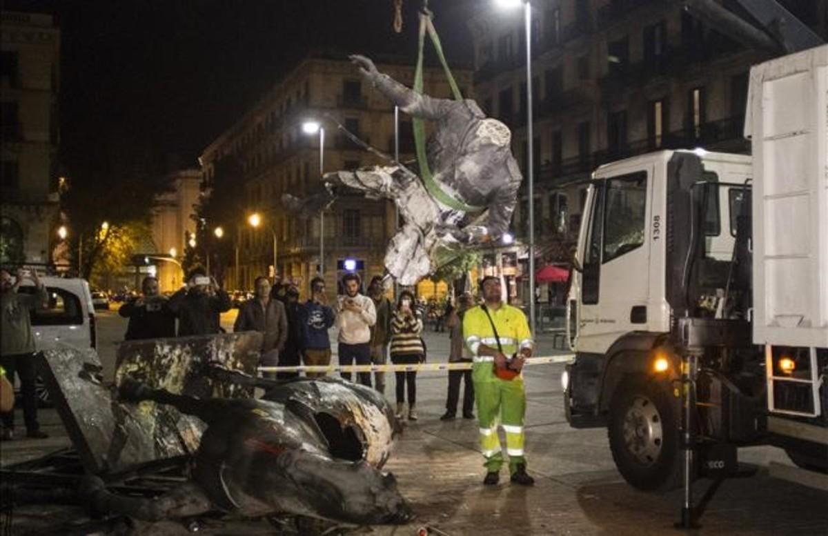 Unos operarios retiran la estatua rota de Franco, en la noche del jueves.