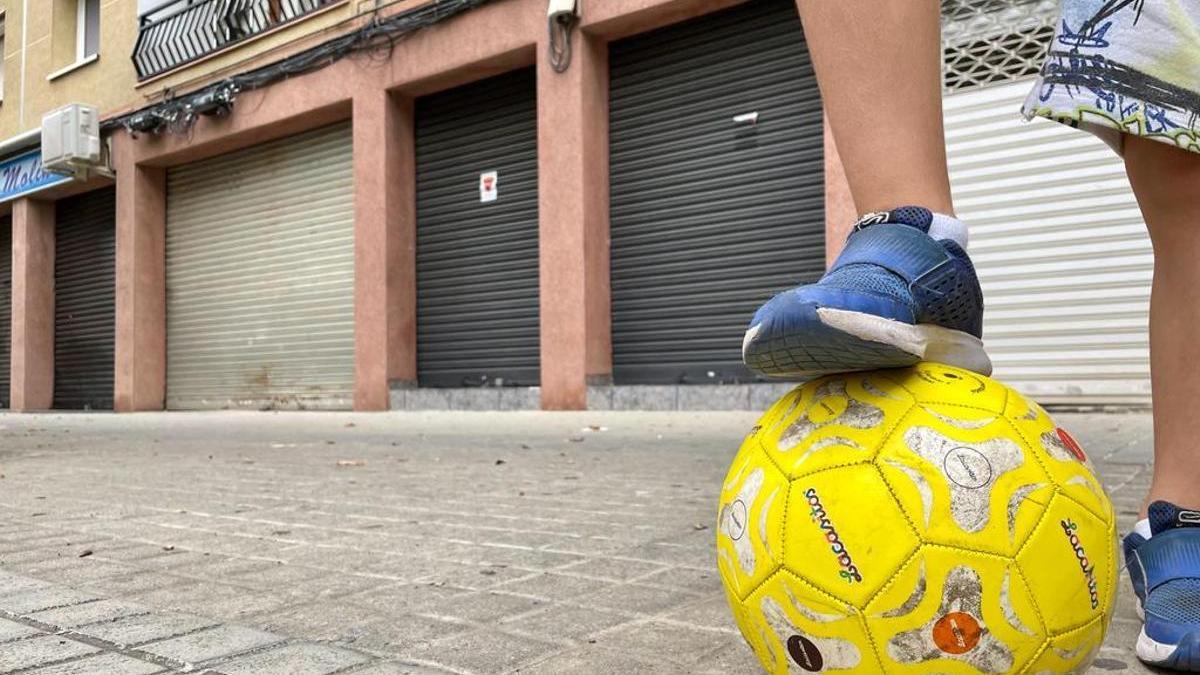 Un niño con balón de fútbol frente al local de la Llagosta del pederasta detenido.