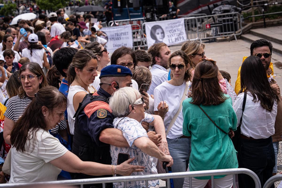 Fieles esperan en la catedral de Barcelona la llegada del papa León XIV. Una mujer se desmaya y es atendida por un agente de los Mossos