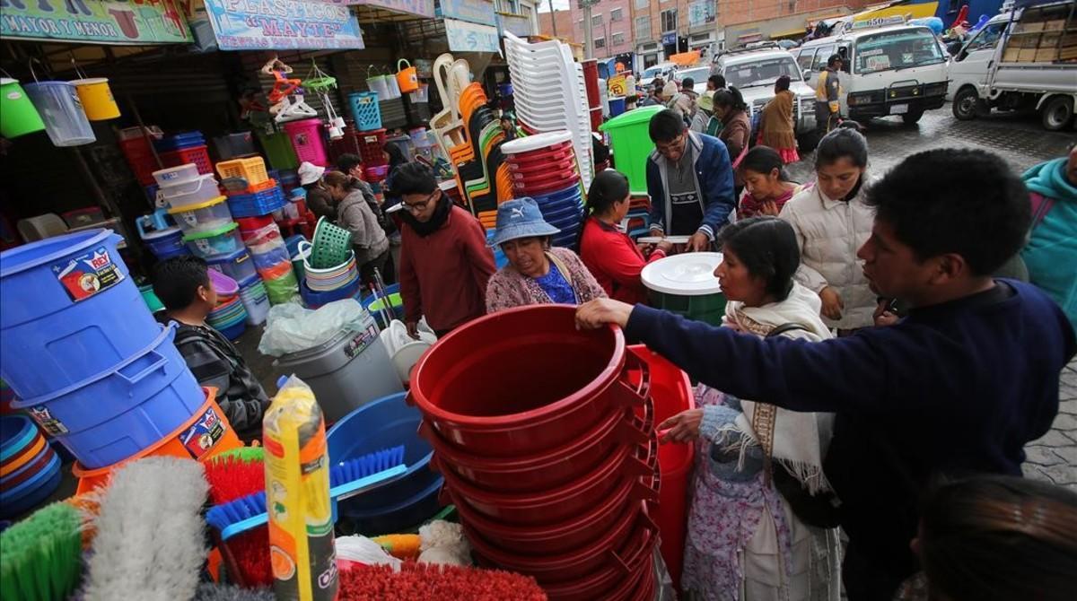 Varias personas compran recipientes plásticos después de producirse algunos cortes de agua, en El Alto, este lunes.