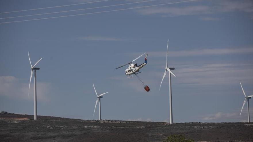 Un helicóptero con la carga de agua en la zona del incendio y entre los molinos del parque eólico. | Emilio Fraile