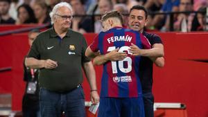 Fermín se abraza a Xavi tras marcar el 1-2 del Barça en Sevilla ante Carles Naval, el delegado azulgrana.