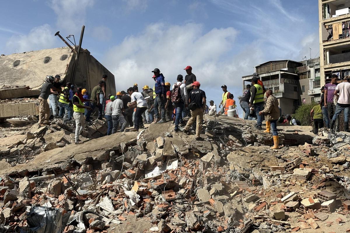 Personas caminan sobre escombros de edificios derrumbados por los terremotos este jueves, en el sector San Bernardino, en Caracas (Venezuela). EFE/ Carlos Seijas