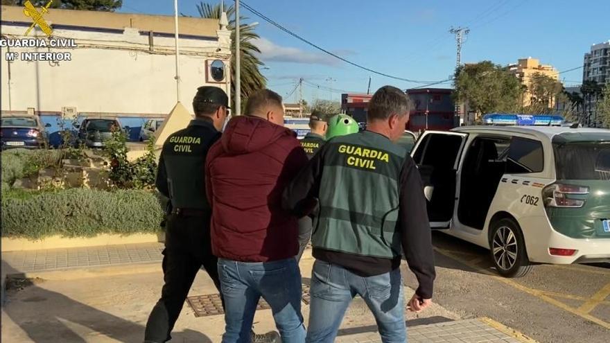 Dos guardias civiles escoltan al sospechoso tras detenerlo en un piso de Cullera.