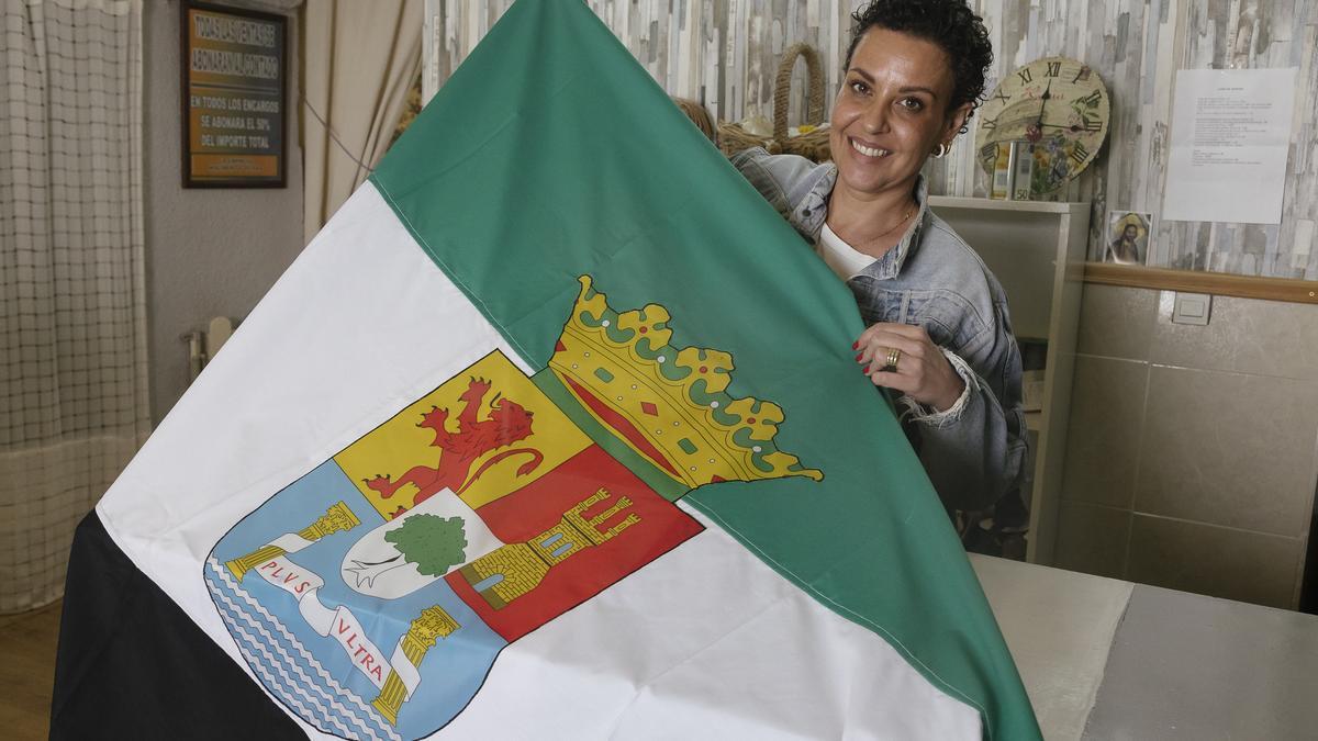 Gema Molinero con una bandera de Extremadura en su negocio.