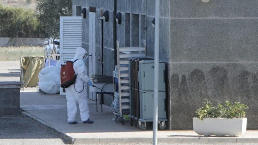 Un operario desinfecta varios artículos en los exteriores de una residencia de El Puig donde se ha detectado un macrobrote.