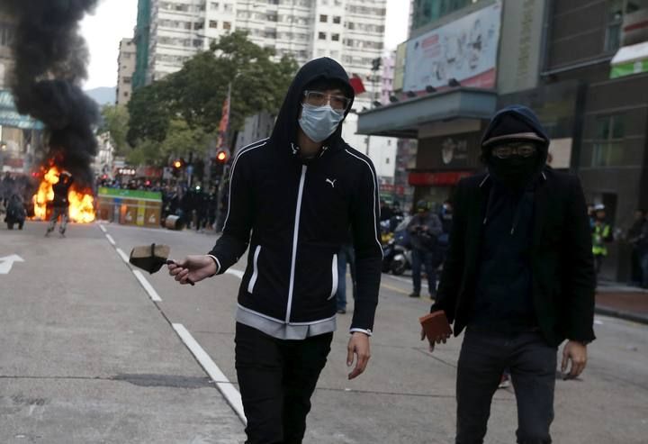 Protesters prepare to throw stones towards riot police after setting fire at a junction in Mongkok district in Hong Kong