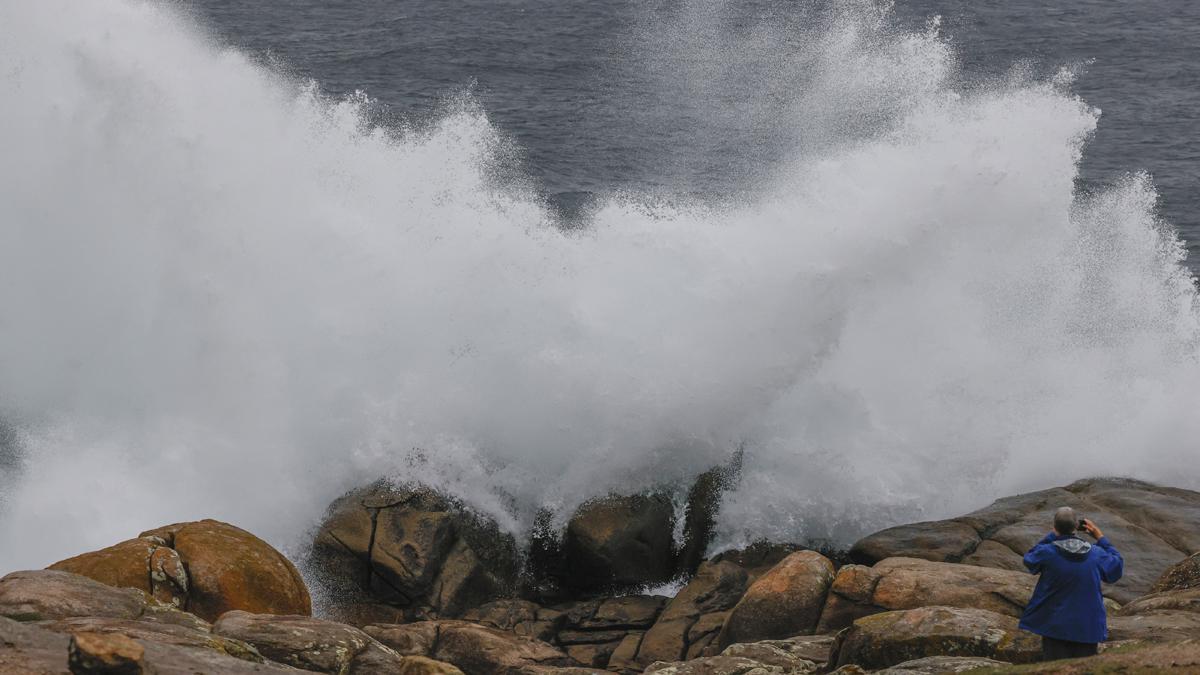 Un turista fotografía las olas en Muxía, durante una borrasca