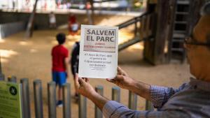 Un vecino sostiene un cartel opuesto a las obras de un instituto dentro del jardín Doctor Comas i Llaberia, en el barrio de Vallcarca, en Barcelona.