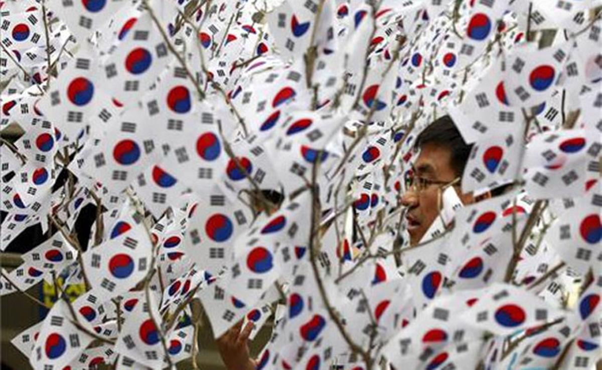 Desenes de banderes coreanes envolten un home que celebra a Seül el Dia de l’Alliberament Coreà del domini japonès.