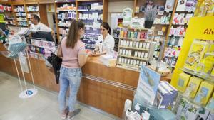 Farmacéuticos y clientes sin mascarilla en una farmacia del distrito de Carabanchel, en Madrid