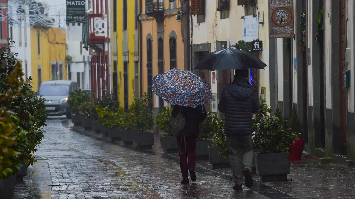 Dos personas transitan por una calle de San Mateo durante un día de lluvia.