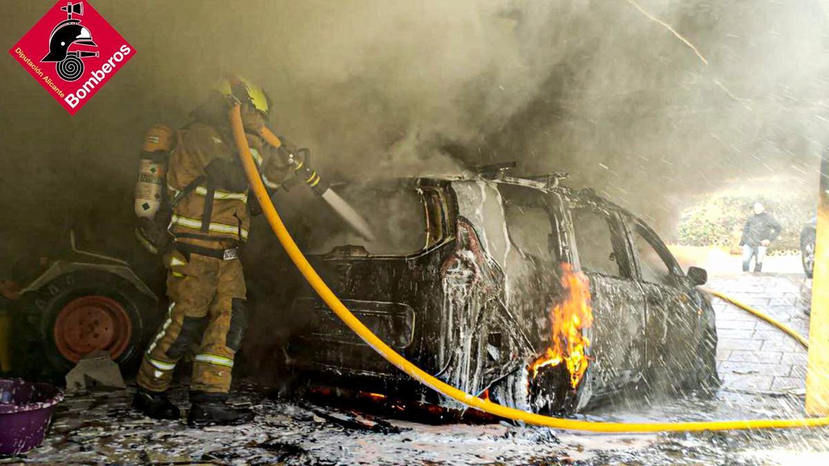 Los bomberos extinguen las llamas en uno de los vehículos calcinados.