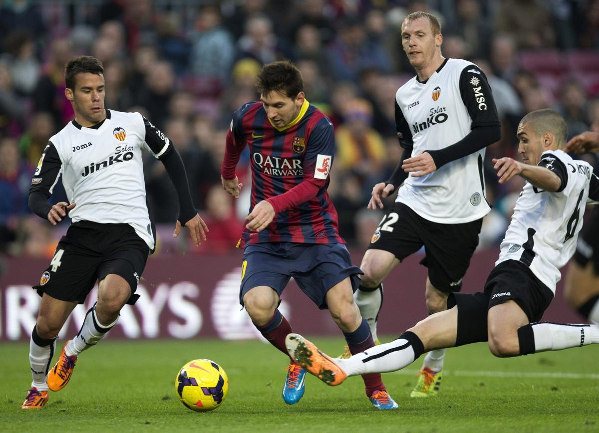 Intentando derribar a Messi en el Barça-Valencia de 2014.