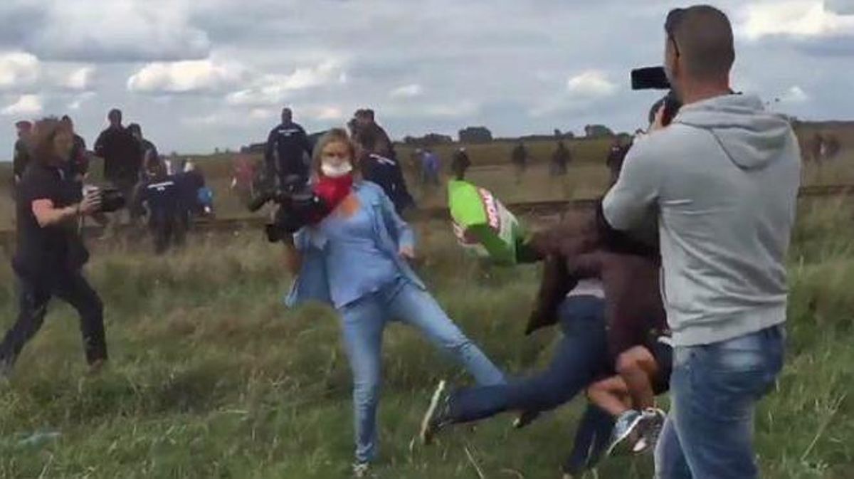 Fotograma en què es pot veure la reportera fent la traveta a un refugiat amb un nen als braços.