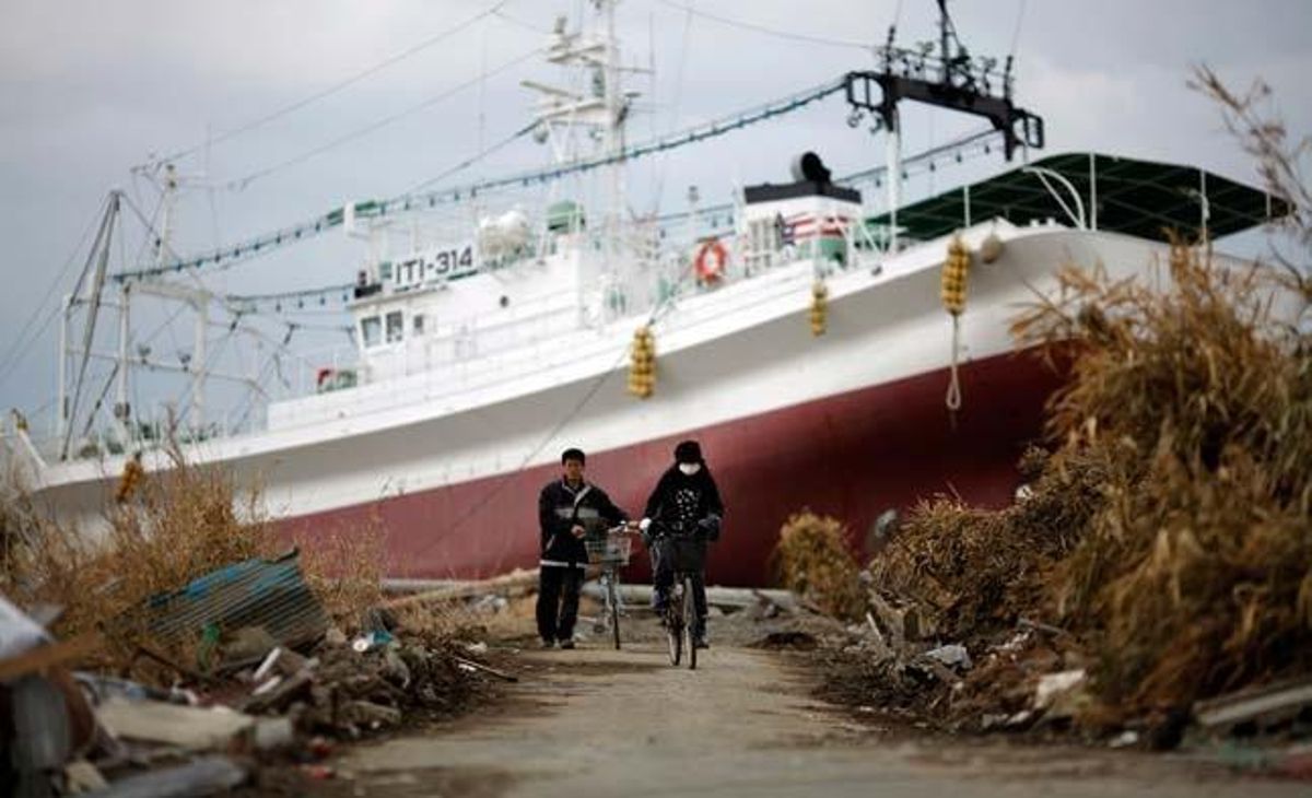 Una dona va en bicicleta davant d’un vaixell encallat a terra ferma com a conseqüència del tsunami a Ishinomaki, al nord del Japó.
