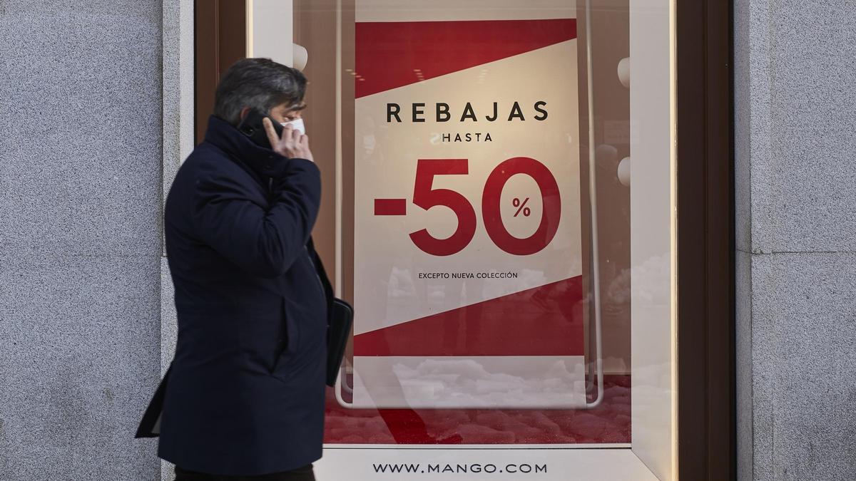 Un hombre camina frente a un cartel de rebajas en Madrid.