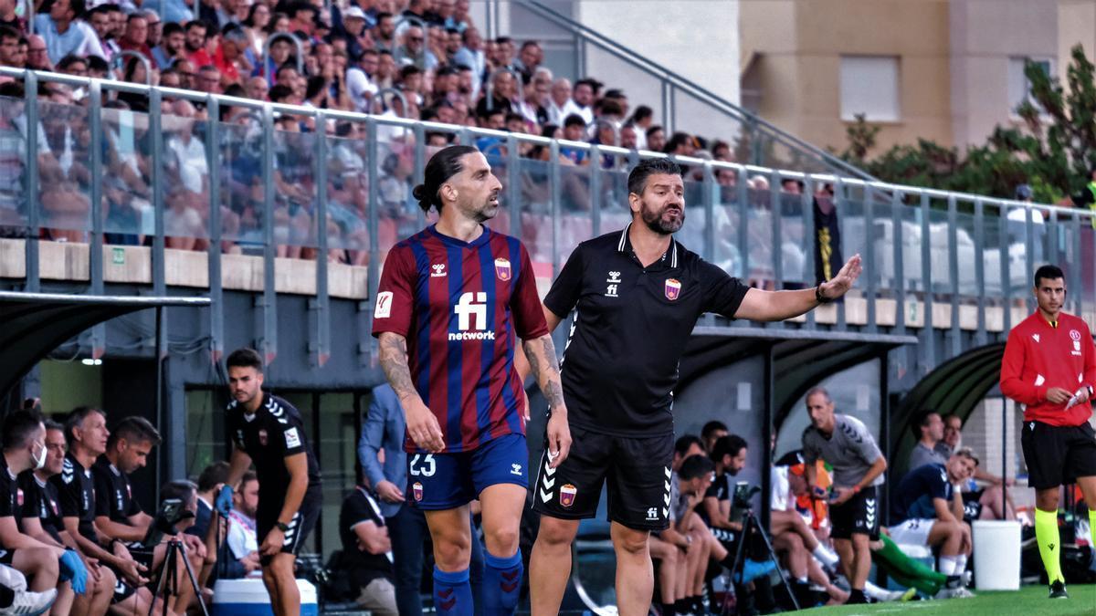 Fernando Estévez pide calma a sus futbolistas con la tribuna a su espalda repleta de aficionados.