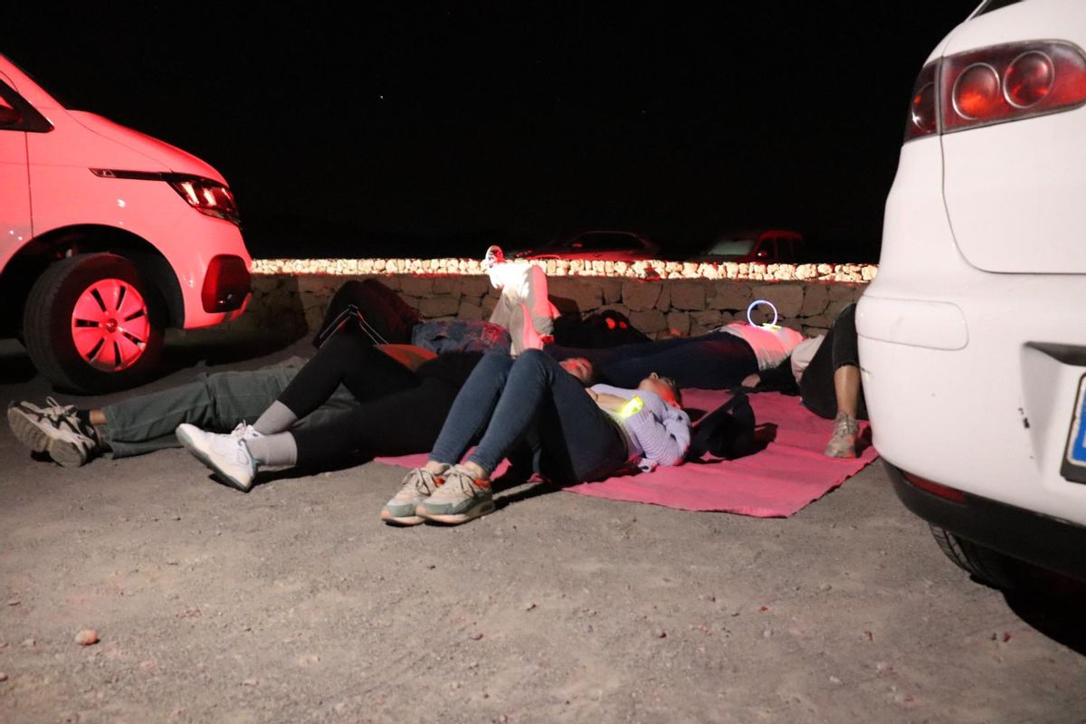 Un grupo despliega una manta en pleno parking de Las Minas de San José para contemplar las estrellas.