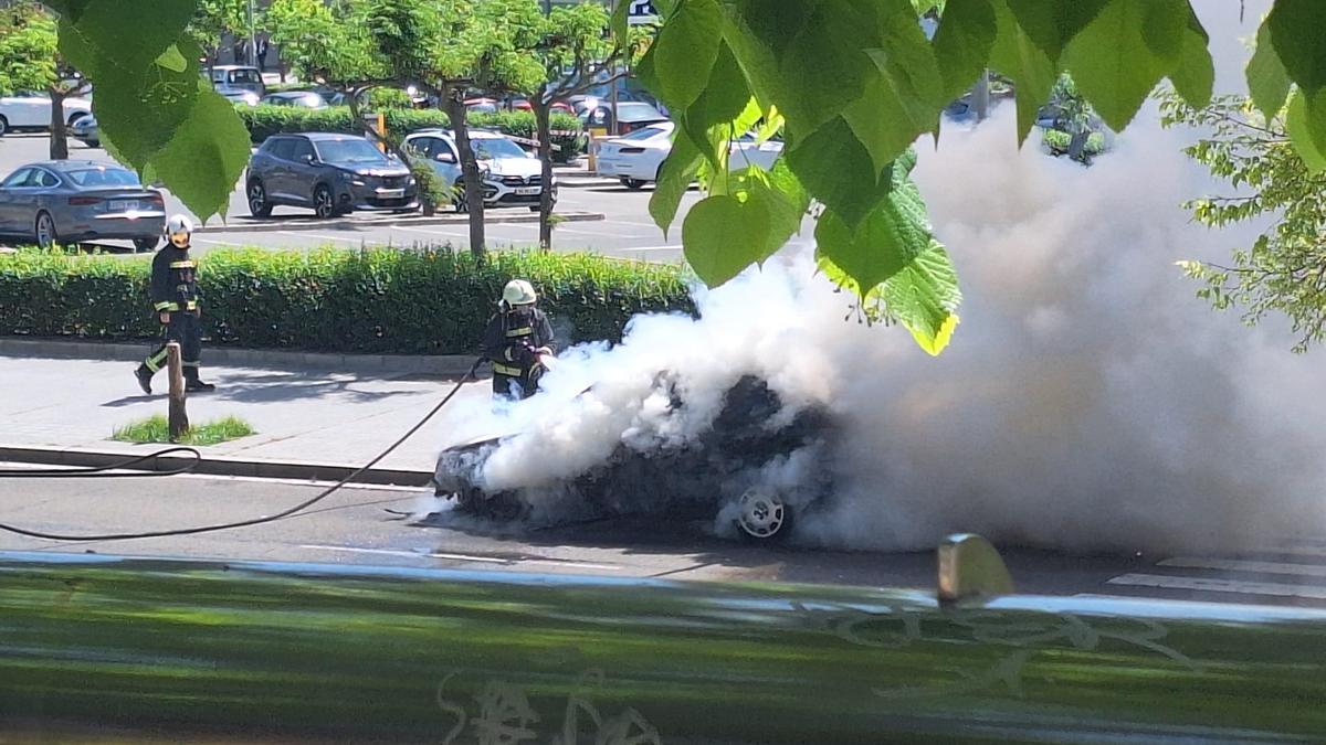 Los bomberos tratan de apagar un incendio de un coche en Avenida de los Piconeros.