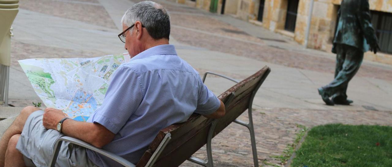 Un turista consulta un mapa en un banco de la ciudad.  | Jose Luis Fernández