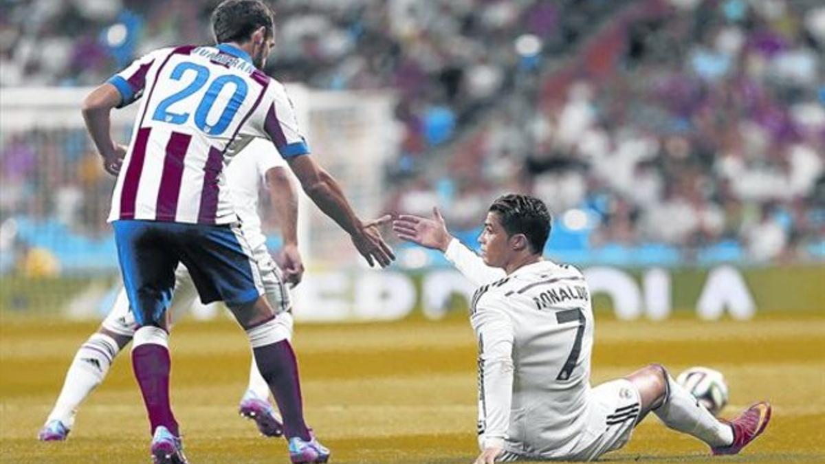 Juanfrán trata de socorrer a Cristiano Ronaldo, caído, en la primera parte, anoche en el Bernabéu.