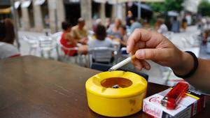 Una persona fumando un cigarro en una terraza.