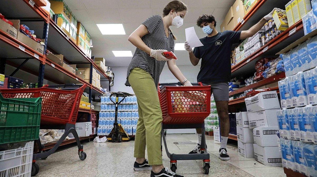 Dos jóvenes preparan paquetes de alimentos en un economato gestionado por Cáritas en Torrent, el 12 de mayo. Dos jóvenes preparan paquetes de alimentos en un economato gestionado por Cáritas en Torrent, el 12 de mayo.