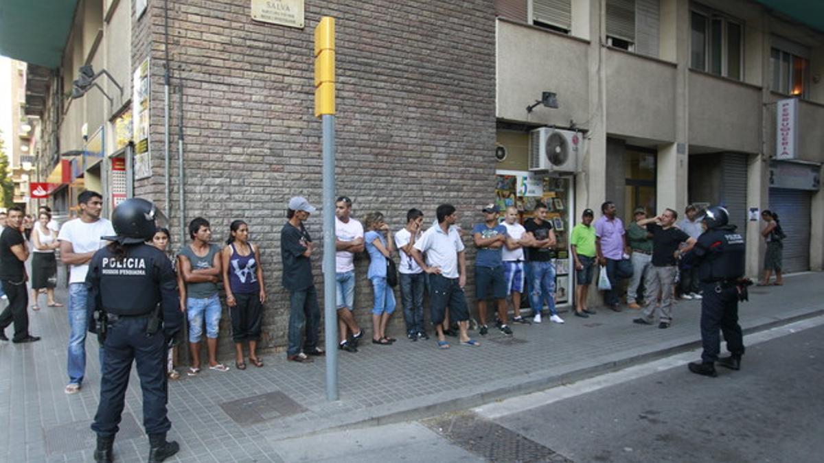 Dos mossos vigilan a un grupo de personas durante la redada contra carteristas rumanos en el Poble Sec.